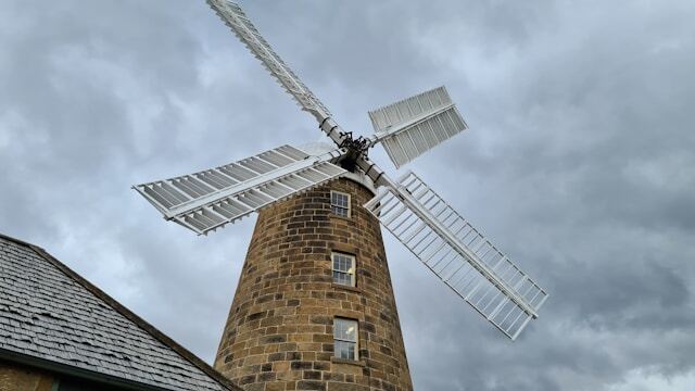 Weathered wind mill made of reddish bricks in front of gloomy skies